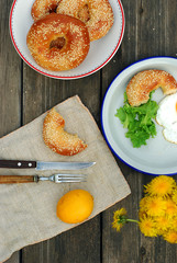 Bagels with sesame seeds on a table with a bouquet of dandelions and lemon for breakfast
