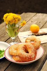 Bagels with sesame seeds on a table with a bouquet of dandelions
