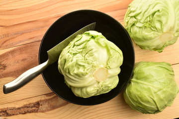 Fresh green cabbage in a black plate, on a wooden table.