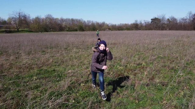Children running along a field on a cold and sunny day in Europe having fun will Drone is filming from above