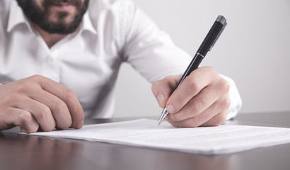 Businessman signing contract in office.