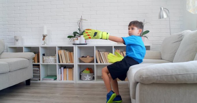 A six years old boy playing soccer football with goalkeeper's gloves at home during quarantine COVID-19. Life stile in apartment. 4k