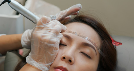 Fototapeta premium Woman undergo eyebrow microblading, permanent makeup