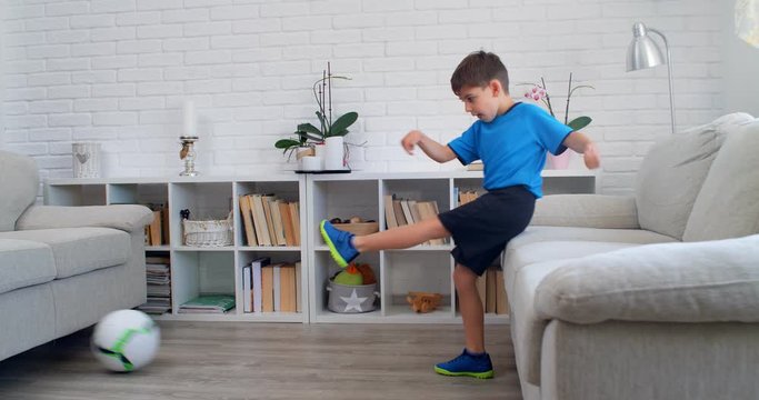 A six years old boy playing soccer football at home during quarantine COVID-19. Life stile in apartment. 4k