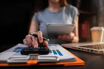 Female businessman working with holding a pen and using a calculator to calculate the numbers of...