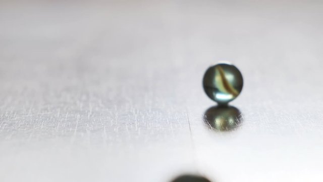 glass marbles flow and collide, close up, slow motion.