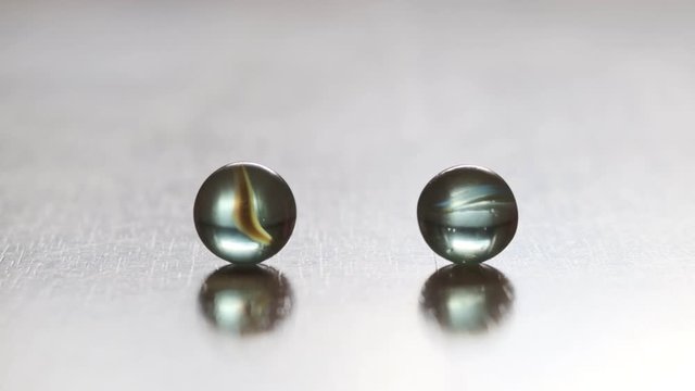 glass marbles flow and collide, close up, slow motion.