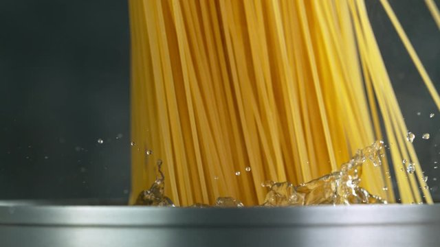 Throwing pasta spaghetti into boiled water in pot shooting with high speed cinematic camera at 1000 fps.