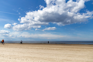 Sandy beach by the sea on a sunny day with white cumulus clouds in the sky.
