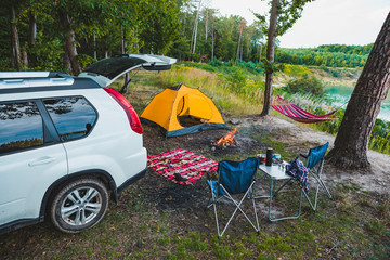 suv car at lake beach camping fire and hammock between trees