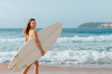 Beautiful sexy surfer girl standing on the beach with surf desk.