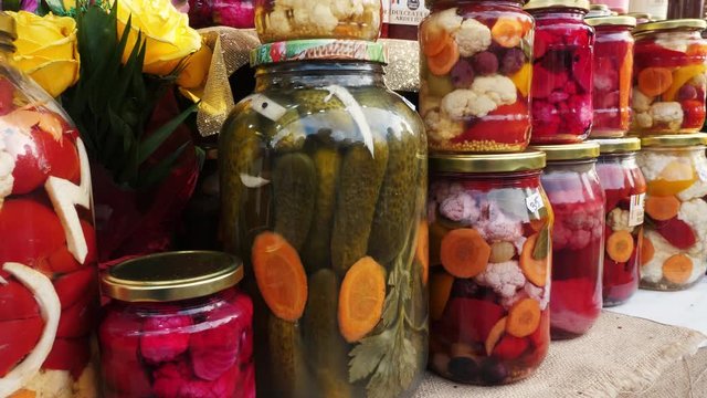 Close up of many jars with pickles at the shopping stand. Various pickles in the jar. Fermented vegetables in the jar.