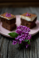 Obraz na płótnie Canvas lilac on wooden boards on a background of cake. flowers with sweet pastries on a plate