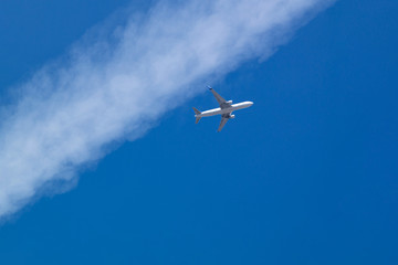 Passenger airliner flies in a blue sky with line clouds.