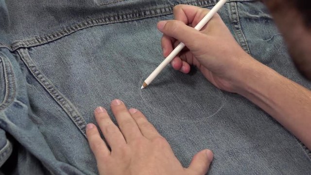 Man Sketching and Drawing on a Denim Jacket with White Pencil