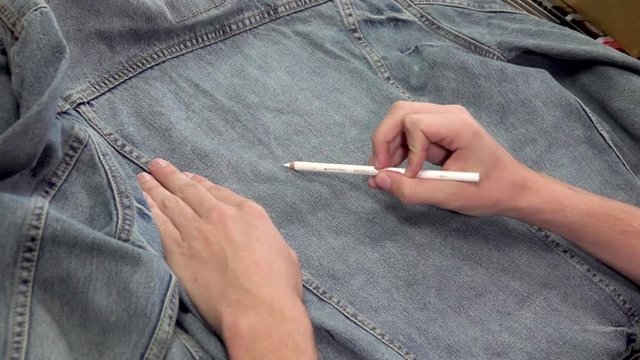 Man Sketching and Drawing on a Denim Jacket with White Pencil