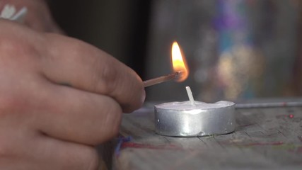 Close Up of Man lighting a small wax candle with a Match