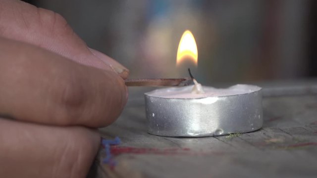 Close Up of Man lighting a small wax candle with a Match