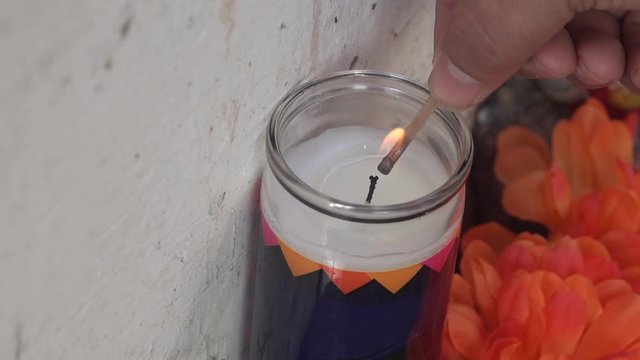Man Lighting a Day of the Dead Candle with a Match during Dia de los Muertos Celebration