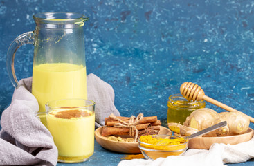 Organic turmeric milk. Composition of glass and decanter with golden milk, ingredients and honey on...