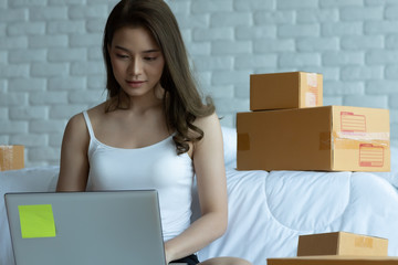 Asian women working with laptop for Online shopping at home with box for packaging in home,Own Small Business Start up for Online shopping.Small business concept.