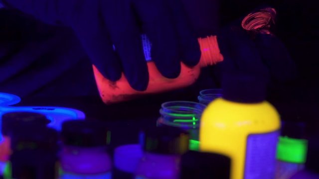 person pouring neon glow in the dark acrylic paint