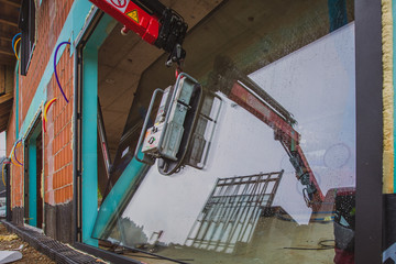 Installing a big glass window into a window frame using a vacuum crane or arm mounted on a flatbed truck. Professional glass installers at work in a new house.