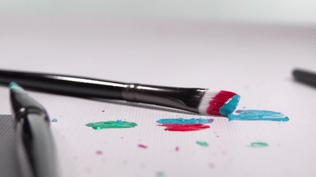 Acrylic Paint Brush falling and Splattering Paint onto White Background in Slow Motion 