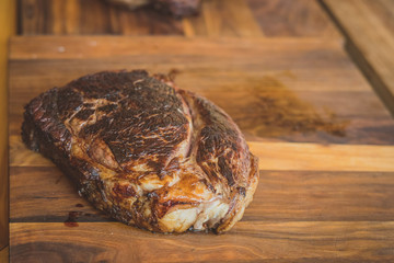 A big piece of beef steak ready to be chopped into smaller pieces in a wooden table.