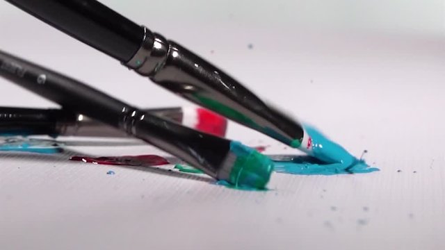 Paint Brushes falling onto White Background and Splattering Paint in Slow Motion, Close Up