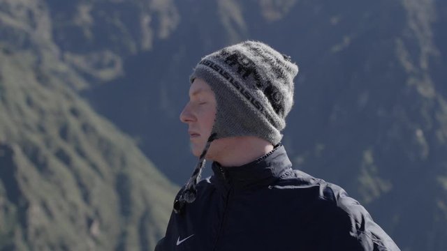 Medium close-up of caucasian male with traditional Peruvian hat on smiling and enjoys the view over Colca Canyon in Peru
