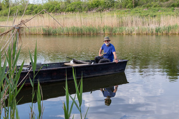 Fototapeta na wymiar Senior fisherman in a boat at Danube-Tisa-Danube channel near Novi Sad, Serbia.