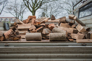 Logs of wood or chunks of timber loaded on a flat bed of a pickup or truck, ready to be transported to a house. Firewood ready for transportation © Anze