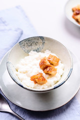 Creamy Rice Porridge or Pudding with caramelized bananas in bowl on grey concrete background. Selective focus