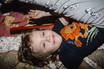 .happy boy of three years plays in bed and laughs. Close-up