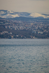 Panorama of the suburbs of Rijeka, Croatia in a cold winter day, with visible snow on the mountains in the background.