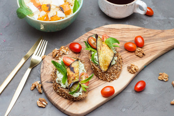 Bruschetta with grilled eggplant, cherry tomatoes, cheese dip, fresh basil and aromatic herbs. Mediterranean cuisine.