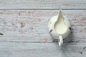 Top view of a pitcher full of fresh milk on wooden table. Copy space