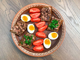 Morning breakfast. Sandwiches with fish Tuna on a clay plate, eggs, tomatoes and green onions. Healthy eating