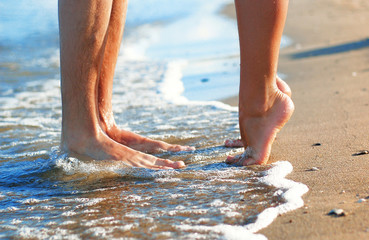 feet of kissing couple at sea shore