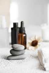 Spa treatment and relax concept. Hot stone massage setting, essential oil bottle and towel.