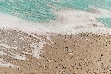 Ocean wave on a sandy beach in the sunset light for background use