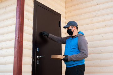 A young employee of the delivery company brought the package to a private house. He knocks on the door. Business and help concept.