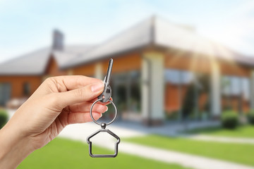 Woman with key near new modern house outdoors, closeup