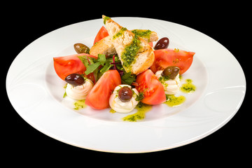 Tasty Salad Caprese with mousse cheese on a plate, isolated on black background.