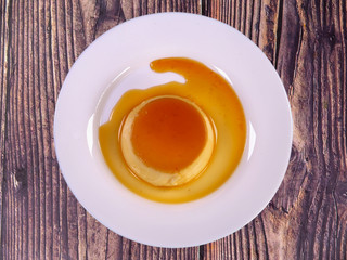 Tasty caramel custard with eggs, milk, and sugar on a plate. top view