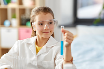 education, science and children concept - girl in goggles with test tube studying chemistry at home laboratory