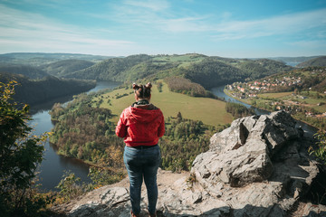 Beautiful girl enjoying life and watching the river, mountains and hills during sunrise on the viewpoint Solenice,Czech republic