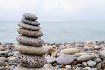 Obraz na płótnie Canvas Pyramid of sea stones on the seashore at the pebble beach. Concept of harmony and balance.
