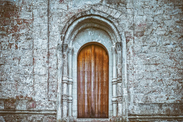 Stone fortress wall of a medieval castle, old wooden closed front door.